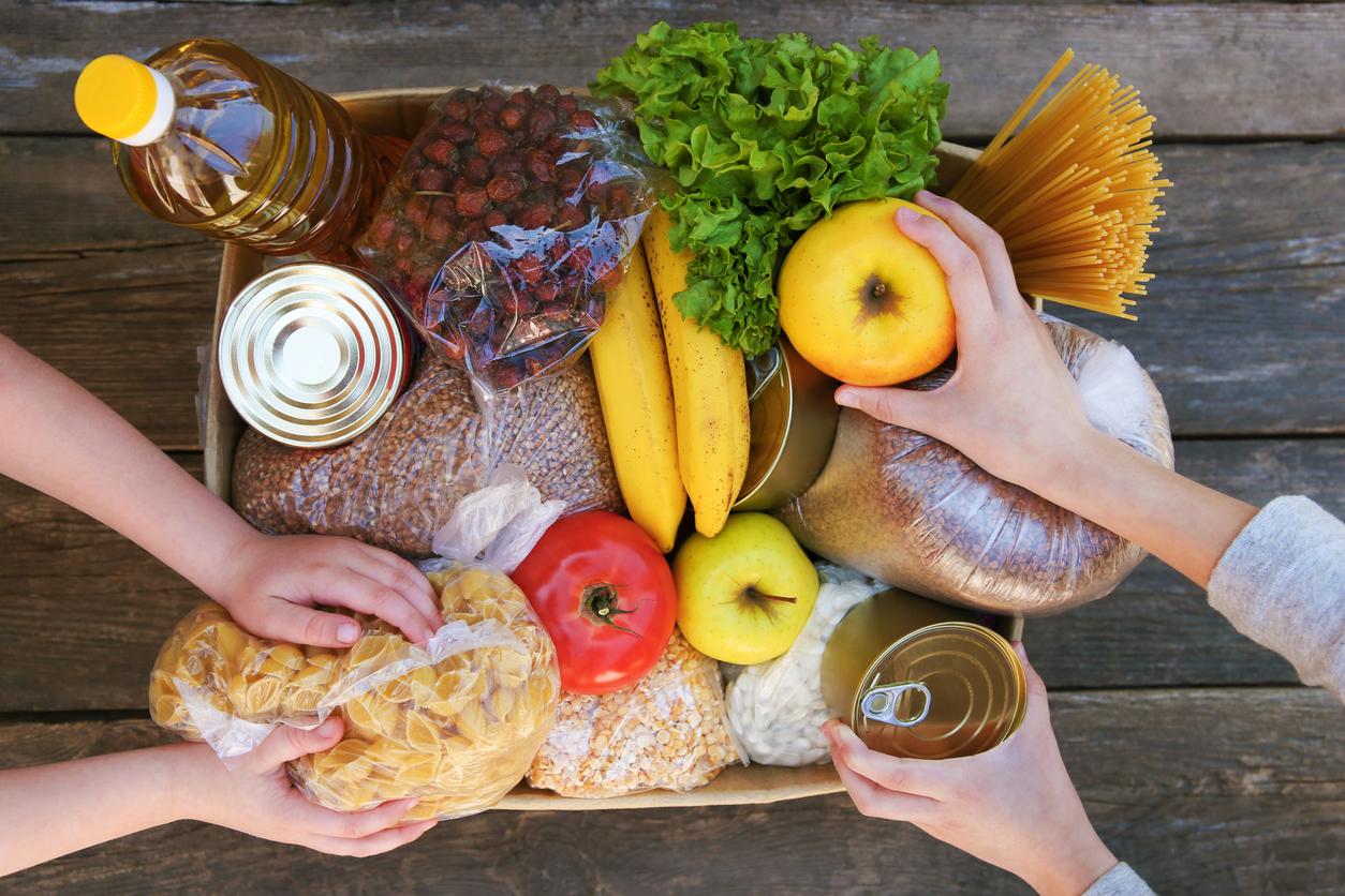 Hands reach into a box filled with food donations.